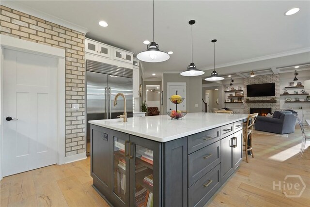 315 Linkside Lake Dr, Richmond Hill, GA 31324 - kitchen featuring ornamental molding, gray cabinetry, a kitchen island with sink, a brick fireplace, and light countertops