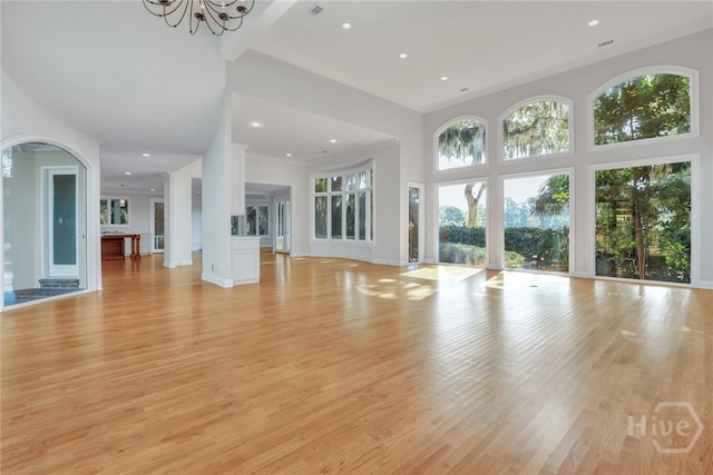 3 Elcy Ln, Savannah, GA 31411 - unfurnished living room with light wood-type flooring, a chandelier, recessed lighting, a high ceiling, and baseboards