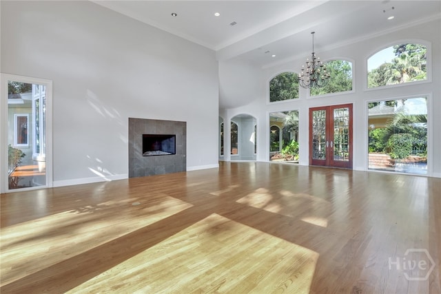 3 Elcy Ln, Savannah, GA 31411 - unfurnished living room with a towering ceiling, healthy amount of natural light, a fireplace, a chandelier, and ornamental molding