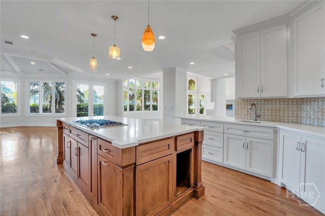 3 Elcy Ln, Savannah, GA 31411 - kitchen with stainless steel gas cooktop, a sink, light wood finished floors, open floor plan, and backsplash