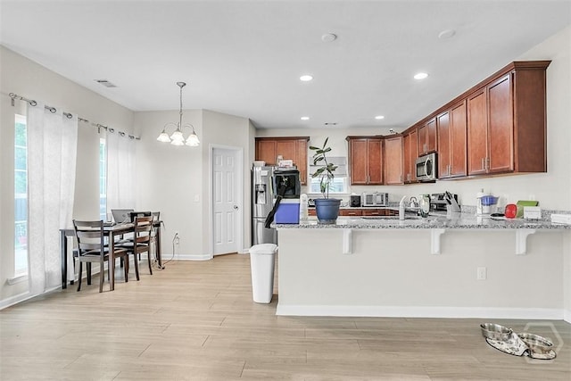 194 Calm Oaks Cir, Savannah, GA 31419 - kitchen with stainless steel appliances, a peninsula, light wood-style floors, a chandelier, and a kitchen bar