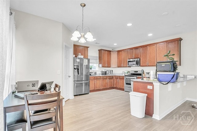 194 Calm Oaks Cir, Savannah, GA 31419 - kitchen with appliances with stainless steel finishes, a chandelier, light wood-style floors, brown cabinets, and a peninsula