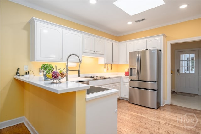6 Pine Shadow Ct, Savannah, GA 31411 - kitchen with stainless steel fridge, a peninsula, white cabinets, light wood-style flooring, and a skylight