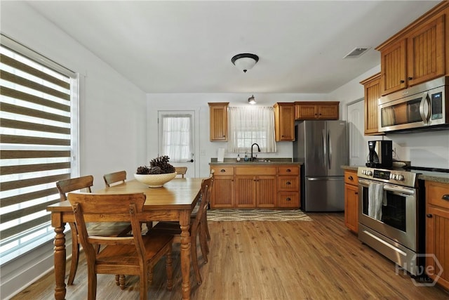 152 Covey Rise Pl, Midway, GA 31320 - kitchen featuring appliances with stainless steel finishes, a sink, wood finished floors, brown cabinets, and dark countertops