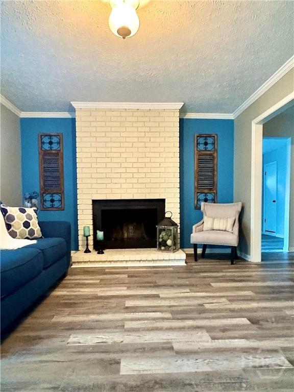 309 Middleton St S, Pooler, GA 31322 - living area with a textured ceiling, wood finished floors, a brick fireplace, ornamental molding, and baseboards