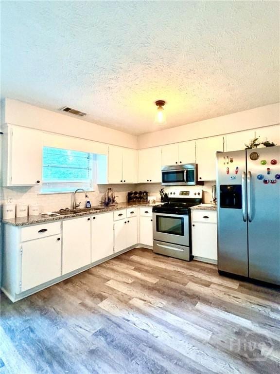 309 Middleton St S, Pooler, GA 31322 - kitchen featuring appliances with stainless steel finishes, a sink, a textured ceiling, light wood-style flooring, and white cabinets