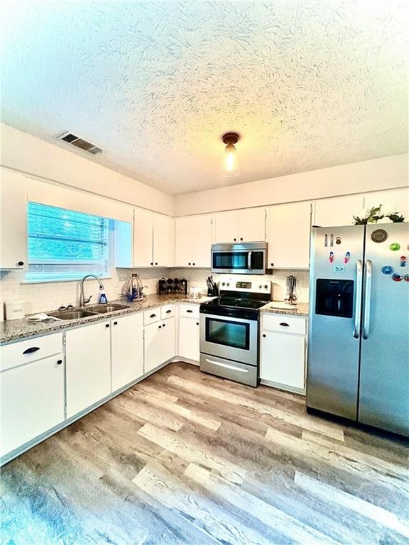 309 Middleton St S, Pooler, GA 31322 - kitchen featuring appliances with stainless steel finishes, a textured ceiling, a sink, white cabinets, and light wood-type flooring