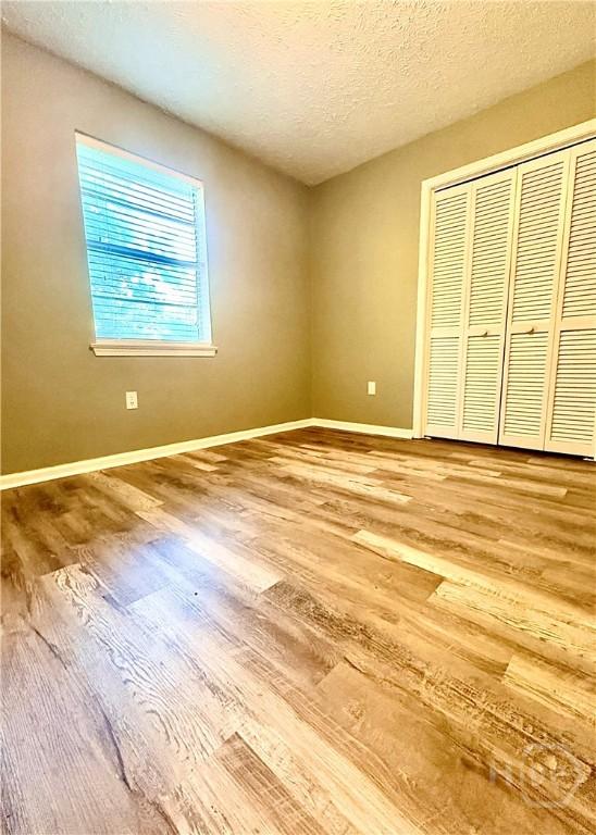 309 Middleton St S, Pooler, GA 31322 - unfurnished bedroom with wood finished floors, baseboards, a closet, and a textured ceiling