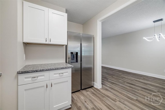 405 E 3rd St, Springfield, GA 31329 - kitchen featuring stainless steel refrigerator with ice dispenser, light wood-style flooring, white cabinets, decorative light fixtures, and a textured ceiling