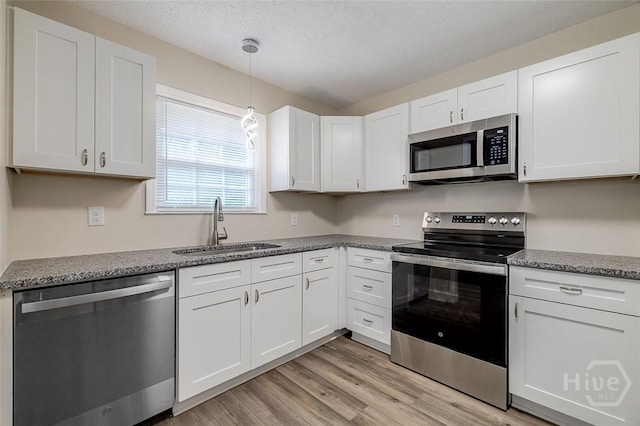 405 E 3rd St, Springfield, GA 31329 - kitchen featuring appliances with stainless steel finishes, a sink, light wood finished floors, white cabinetry, and pendant lighting
