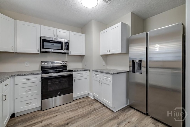 405 E 3rd St, Springfield, GA 31329 - kitchen with appliances with stainless steel finishes, light wood finished floors, white cabinetry, a textured ceiling, and light stone counters