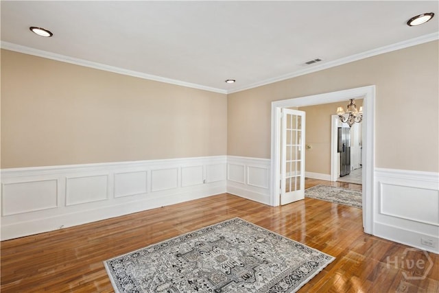 1319 E 39th St E, Savannah, GA 31404 - unfurnished room featuring a chandelier, wood finished floors, ornamental molding, and wainscoting