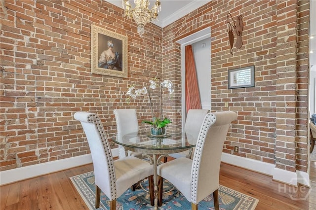 509 E Broughton St, Savannah, GA 31401 - dining room with baseboards, hardwood / wood-style flooring, ornamental molding, brick wall, and a chandelier