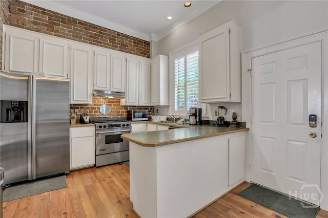 509 E Broughton St, Savannah, GA 31401 - kitchen featuring appliances with stainless steel finishes, under cabinet range hood, crown molding, a peninsula, and white cabinetry