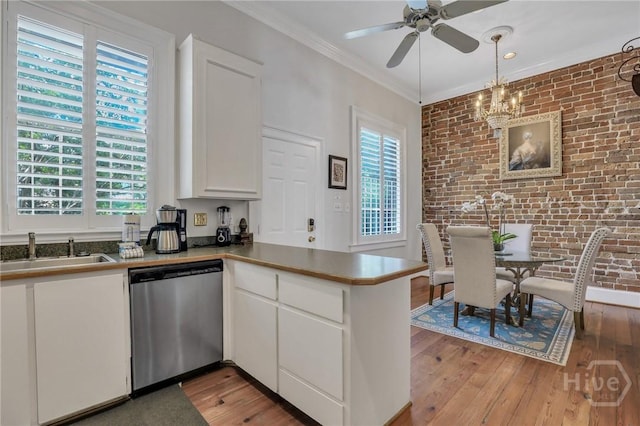 509 E Broughton St, Savannah, GA 31401 - kitchen featuring dishwasher, a sink, brick wall, a peninsula, and white cabinetry