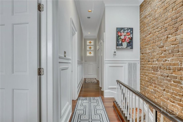 509 E Broughton St, Savannah, GA 31401 - corridor featuring a decorative wall, dark wood finished floors, brick wall, wainscoting, and crown molding