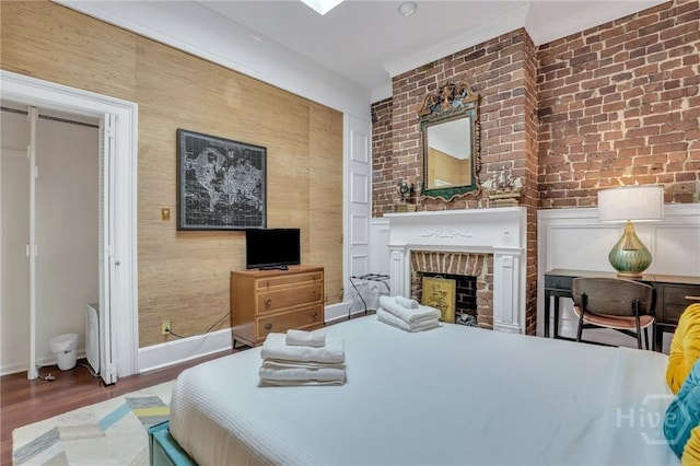 509 E Broughton St, Savannah, GA 31401 - bedroom with wood finished floors, a fireplace, brick wall, and baseboards