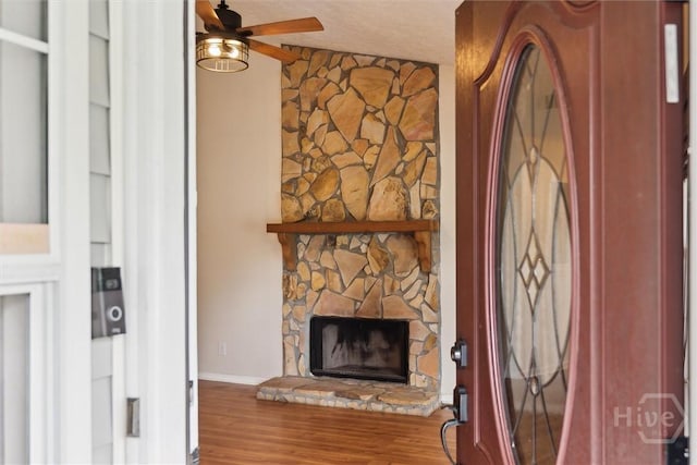 207 Whippoorwill Ln E, Richmond Hill, GA 31324 - unfurnished living room featuring a ceiling fan, wood finished floors, a stone fireplace, and baseboards