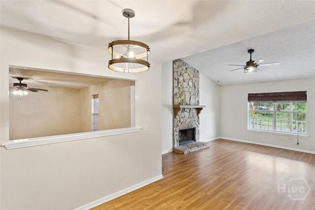 207 Whippoorwill Ln E, Richmond Hill, GA 31324 - unfurnished living room with a ceiling fan, vaulted ceiling, wood finished floors, baseboards, and a stone fireplace