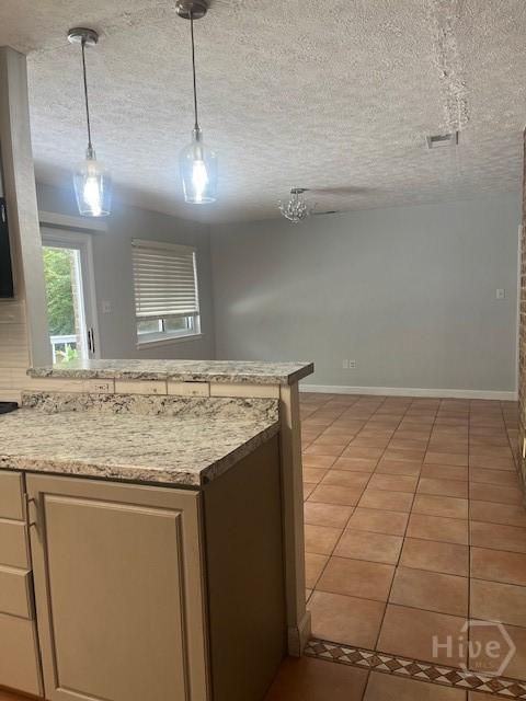 5 Chesterfield Ct, Savannah, GA 31419 - kitchen with light tile patterned floors, light countertops, a textured ceiling, a peninsula, and decorative light fixtures