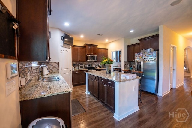 66 Tarbert Cut Cut, Richmond Hill, GA 31324 - kitchen with appliances with stainless steel finishes, a sink, a kitchen island, decorative backsplash, and dark wood finished floors