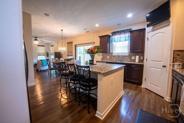 66 Tarbert Cut Cut, Richmond Hill, GA 31324 - kitchen with a kitchen island, a kitchen bar, dark brown cabinetry, dark wood-style floors, and decorative backsplash