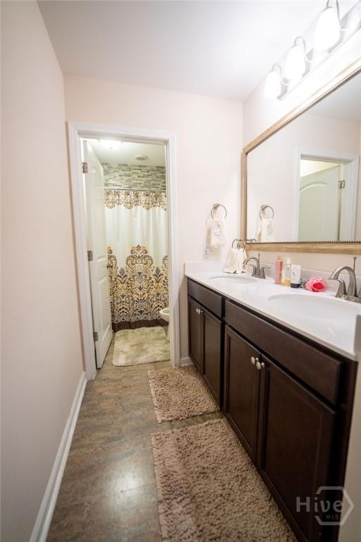 66 Tarbert Cut Cut, Richmond Hill, GA 31324 - bathroom with double vanity, baseboards, toilet, and a shower with shower curtain
