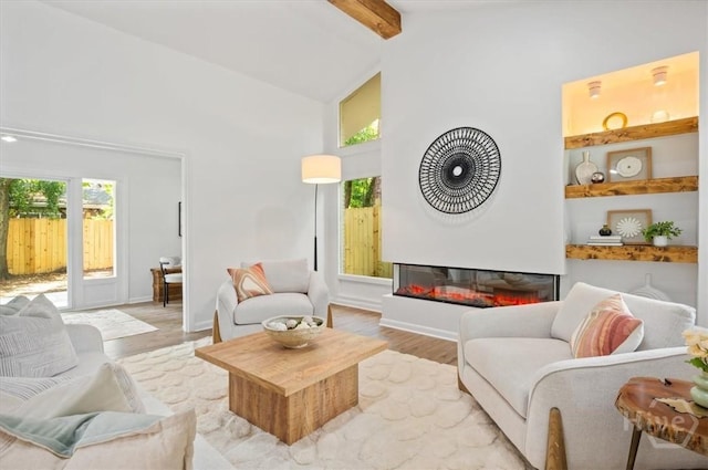 4750 Sylvan Dr, Savannah, GA 31405 - living area featuring light wood-style floors, beam ceiling, high vaulted ceiling, a glass covered fireplace, and baseboards