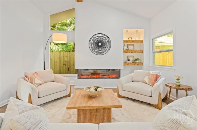 4750 Sylvan Dr, Savannah, GA 31405 - living room featuring vaulted ceiling, wood finished floors, healthy amount of natural light, a glass covered fireplace, and baseboards