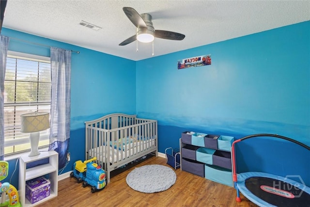 151 Ogeechee Ave, Bloomingdale, GA 31302 - bedroom featuring wood finished floors, a textured ceiling, a ceiling fan, and a crib