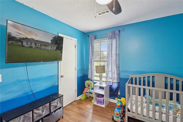 151 Ogeechee Ave, Bloomingdale, GA 31302 - bedroom with wood finished floors, a textured ceiling, a ceiling fan, a crib, and baseboards