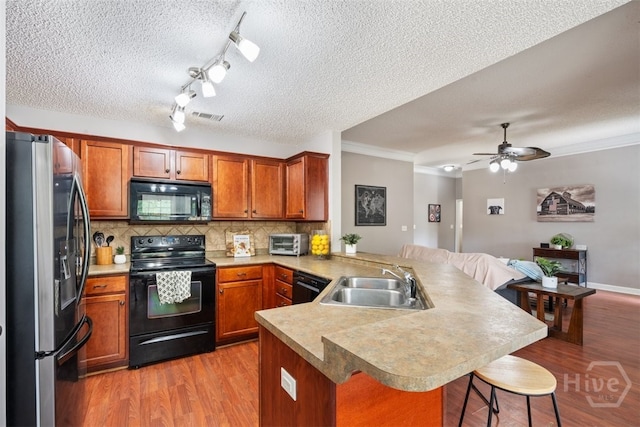 210 Pebblestone Dr, Bloomingdale, GA 31302 - kitchen featuring black appliances, a sink, a peninsula, a kitchen breakfast bar, and decorative backsplash