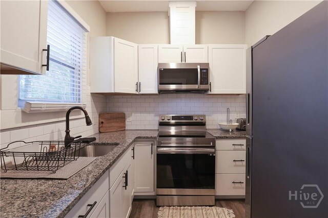 2301 Alaska St, Savannah, GA 31404 - kitchen featuring appliances with stainless steel finishes, white cabinets, stone countertops, dark wood-style floors, and tasteful backsplash