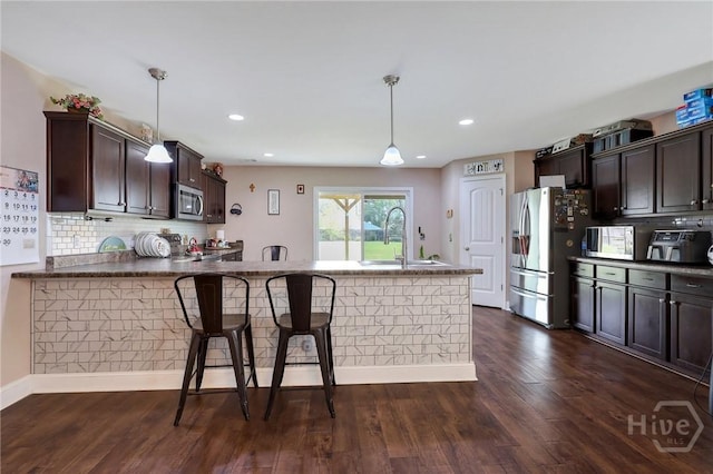 4 Broken Bit Rd, Ellabell, GA 31308 - kitchen with stainless steel appliances, dark brown cabinets, decorative backsplash, a kitchen breakfast bar, and recessed lighting