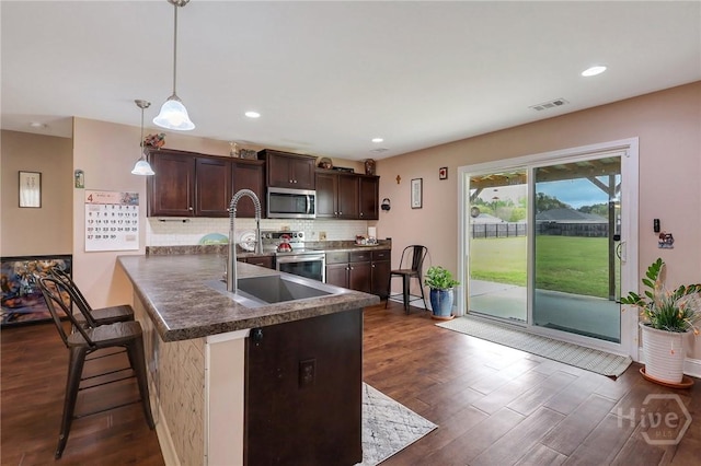 4 Broken Bit Rd, Ellabell, GA 31308 - kitchen featuring appliances with stainless steel finishes, dark brown cabinetry, dark wood-style flooring, dark countertops, and recessed lighting