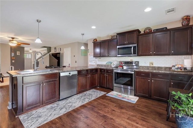 4 Broken Bit Rd, Ellabell, GA 31308 - kitchen with appliances with stainless steel finishes, a peninsula, dark wood finished floors, backsplash, and recessed lighting