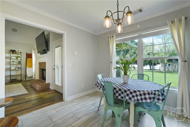510 Braves Field Dr, Guyton, GA 31312 - dining space featuring baseboards, ornamental molding, a chandelier, light wood-type flooring, and a fireplace