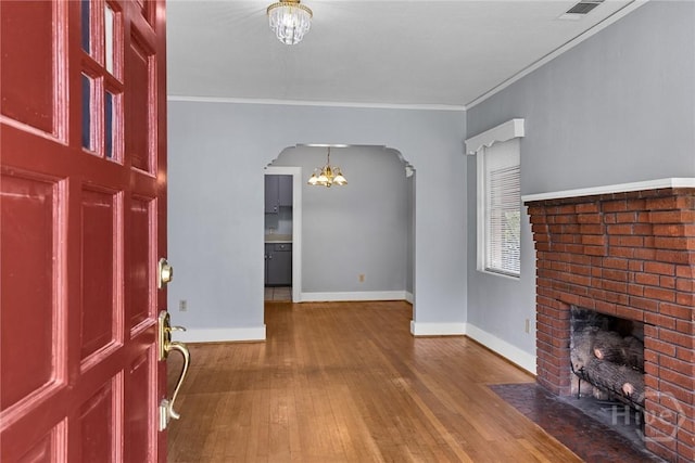 1419 E 35th St, Savannah, GA 31404 - foyer entrance featuring arched walkways, a chandelier, wood-type flooring, a brick fireplace, and crown molding