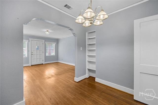 1419 E 35th St, Savannah, GA 31404 - unfurnished dining area featuring arched walkways, crown molding, wood finished floors, and a chandelier