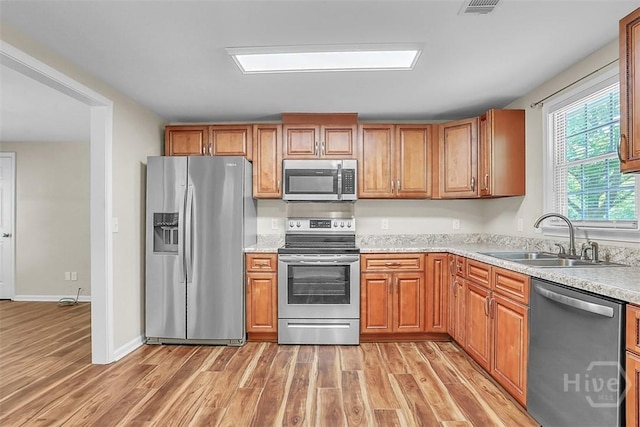 142 Bill Brown Rd, Pembroke, GA 31321 - kitchen with stainless steel appliances, light wood-style floors, and brown cabinetry