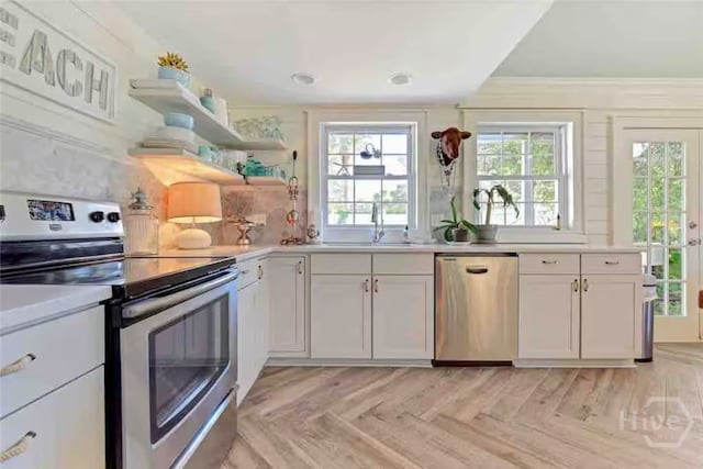 1810 Chatham Ave, Tybee Island, GA 31328 - kitchen with appliances with stainless steel finishes, light countertops, crown molding, white cabinetry, and tasteful backsplash