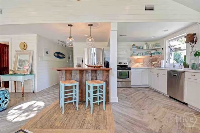 1810 Chatham Ave, Tybee Island, GA 31328 - kitchen with appliances with stainless steel finishes, a breakfast bar area, white cabinetry, light countertops, and pendant lighting