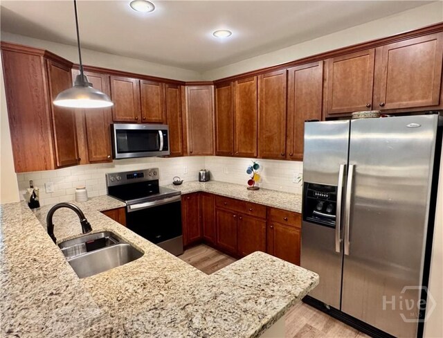 174 Regency Cir, Pooler, GA 31322 - kitchen featuring appliances with stainless steel finishes, a sink, light wood-style floors, light stone counters, and decorative light fixtures