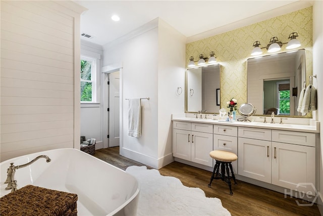 122 N St, Savannah, GA 31410 - bathroom featuring double vanity, a freestanding tub, baseboards, wood finished floors, and wallpapered walls