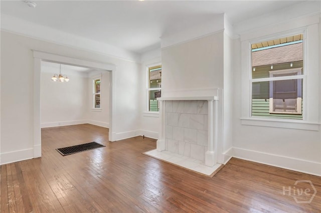 521 Seiler Ave, Savannah, GA 31401 - unfurnished living room with wood-type flooring, a chandelier, baseboards, and a tile fireplace