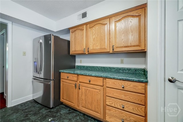 1 Shipyard Ln, Savannah, GA 31406 - kitchen featuring stainless steel fridge with ice dispenser, dark countertops, baseboards, brown cabinets, and a textured ceiling
