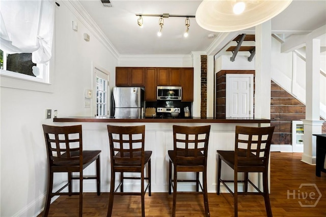 1402 Jefferson St, Savannah, GA 31401 - kitchen with appliances with stainless steel finishes, tasteful backsplash, a breakfast bar, dark wood-style flooring, and crown molding