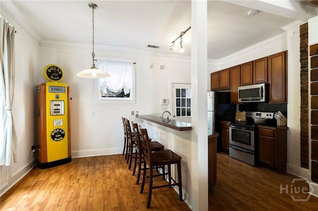 1402 Jefferson St, Savannah, GA 31401 - kitchen with stainless steel appliances, a breakfast bar area, wood finished floors, a peninsula, and ornamental molding
