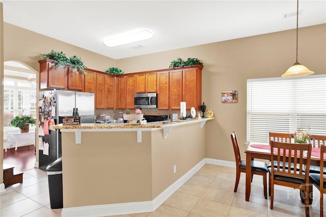 133 Moonlight Trl, Port Wentworth, GA 31407 - kitchen with stainless steel appliances, brown cabinetry, light tile patterned floors, and a peninsula