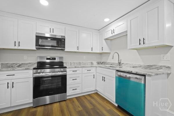 1817 Lloyd St, Savannah, GA 31405 - kitchen with appliances with stainless steel finishes, white cabinets, light stone countertops, dark wood-style flooring, and recessed lighting